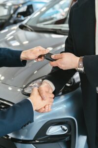 Close-up of a business handshake as car keys are handed over, symbolizing a new car purchase.